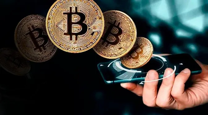 Physical gold Bitcoin coins held alongside a smartphone displaying live crypto market updates.
